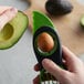 A hand using an OXO Good Grips avocado slicer to cut an avocado.