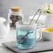 A Fox Run stainless steel tea strainer in a glass mug of blue liquid.