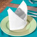 A folded white Intedge cloth napkin on a plate.