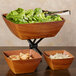 A square faux wood bowl filled with salad on a table.