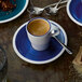 A Villeroy & Boch Artesano Ocean Atlantic Blue porcelain cup of coffee on a saucer with a spoon.