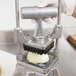 A gloved hand uses a Nemco 1" push block to chop an onion.