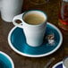 A Villeroy & Boch Pacific Green porcelain saucer with a cup of coffee on it.