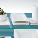 A stack of Villeroy & Boch white rectangular porcelain plates on a glass shelf.