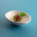A small white oval melamine bowl with a fruit sprig on top.