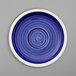 A white porcelain saucer with a blue spiral design on the border.