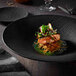 A Villeroy & Boch black shale porcelain plate with food on it on a table.