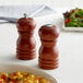 Acopa matte brown wooden salt and pepper shakers on a table.