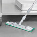 A Unger SmartColor telescoping mop handle with a green edge.