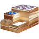 A stackable rectangular wooden display box on a counter with tea containers.