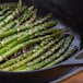 A close up of asparagus in a skillet with sesame seeds.