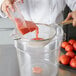 A chef using a Tablecraft fine tin mesh strainer to pour tomato sauce into a container.