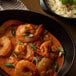 A bowl of shrimp curry next to a bowl of rice with a leafy green garnish.