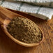 A wooden spoon holding Regal ground cardamom powder on a wood surface.