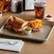 A Baker's Mark gold non-stick aluminum sheet tray with a sandwich, fries, and a drink on it.