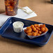 A Baker's Mark blue non-stick tray with fried food in white containers.