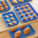 A table with Baker's Mark light blue rimmed trays of pastries.