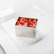 A stainless steel rectangle mold with red fruit inside.