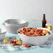A white American Metalcraft melamine serving bowl filled with shrimp and corn on a counter.