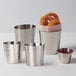 A group of four hammered stainless steel oval cups filled with fries and ketchup.