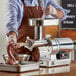 A man in an apron using a Backyard Pro electric meat grinder on a counter.