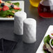 A white American Metalcraft salt and pepper shaker set on a table with a salad.