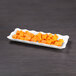 A white Elite Global Solutions rectangular melamine tray with cubes of orange and white food.