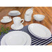 A table set with a stack of white Elite Global Solutions round melamine plates and cups.