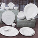 A group of Elite Global Solutions white Merced plates and bowls on a table.