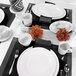 A table set with white Elite Global Solutions oval melamine plates and silverware.