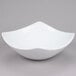 An American Metalcraft white stoneware bowl with a curved edge on a gray background.