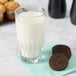 An Anchor Hocking highball glass filled with milk and a chocolate cookie.