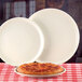 Two Libbey white china pizza platters with pizza on them.