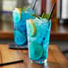 A blue drink with lemon slices and mint leaves in a glass with Monin Premium Blue Cotton Candy Flavoring Syrup.