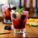 A glass of Monin blackberry sangria with fruit and a lime slice.