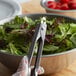 A person using Edlund heavy-duty scallop utility tongs to serve a salad.