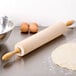 A maple wood Ateco rolling pin and dough on a counter.