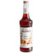 A bottle of Monin Premium Stone Fruit Flavoring Syrup with a white label containing red liquid.
