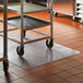 A metal cart on an ES Robbins heavy-duty clear vinyl floor mat.