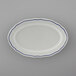 A white Tuxton oval platter with scalloped edges and blue trim.