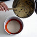 A person mixing dough in a bowl with a Sasa Demarle round white and orange silicone baking mat.