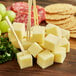 White Sharp Cheddar cheese cubes with crackers and grapes on a table.