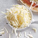 A bowl of shredded Mozzarella cheese.