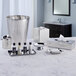 A silver stainless steel soap dish holding small bottles on a marble counter.
