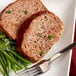 A plate of meatloaf and green beans with a piece of meat.