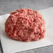 Warrington Farm Meats frozen ground beef in a ball on white paper.
