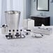 A marble counter with silver trays holding small toiletry bottles and a polished stainless steel tissue box cover.