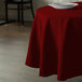 A round table with a burgundy Intedge table cover and a white plate on it.