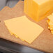 Several slices of Schreiber yellow American cheese on a cutting board.