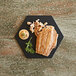A hexagon-shaped slate Richlite wood fiber serving board with a piece of salmon on it.